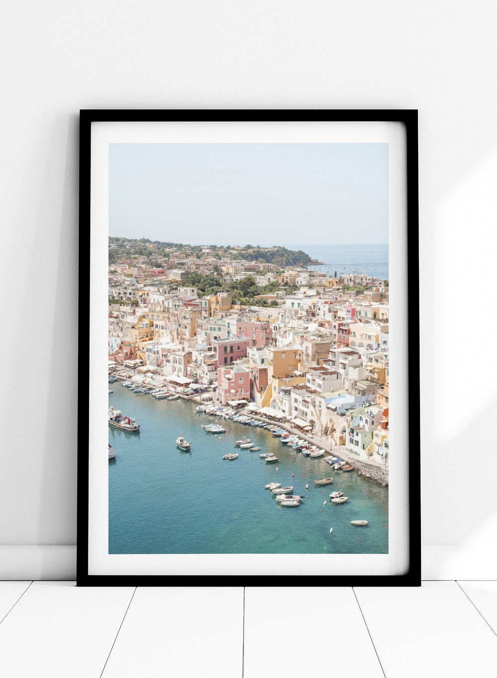 Coastal town with colorful buildings and boats in a harbor. Vibrant Italian Coastal Town by Henrike Schenk is a coastal photography print featuring pastel architecture, turquoise waters, fishing boats, and Mediterranean charm.
