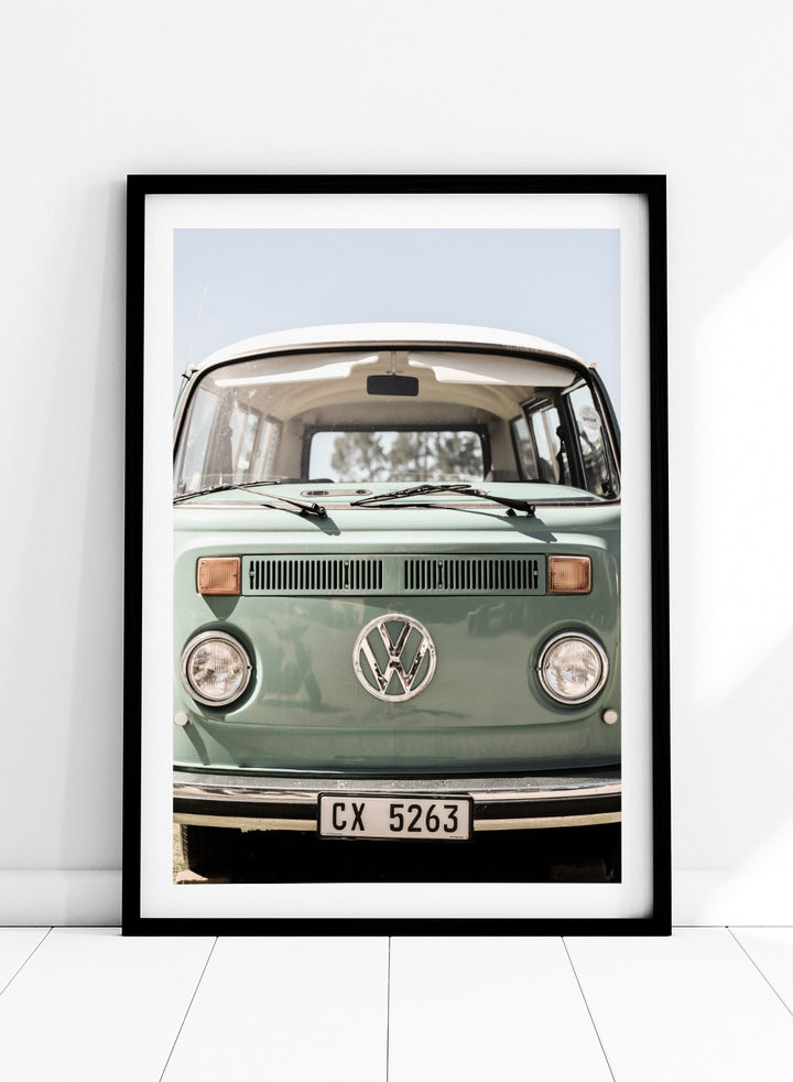 Front view of a vintage green Volkswagen van with clear sky background. Classic Design In Soft Green Tones by Shot by Clint car art print featuring a vintage Volkswagen camper van in soft sage green and warm sunlight.