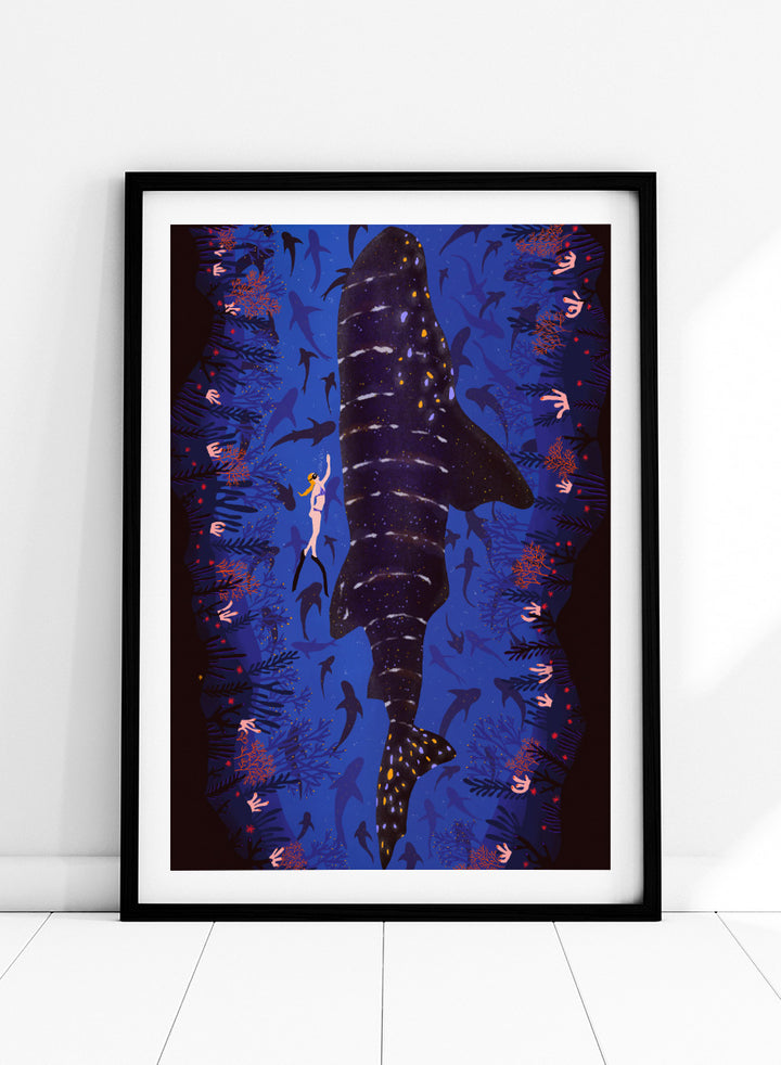 An illustrated art print featuring a large whale shark swimming through a deep blue ocean filled with smaller fish and coral. Diver and Whale Shark art print by Ceyda Alasar features a dramatic underwater view with a whale shark, diver, coral, and rich ocean blues.