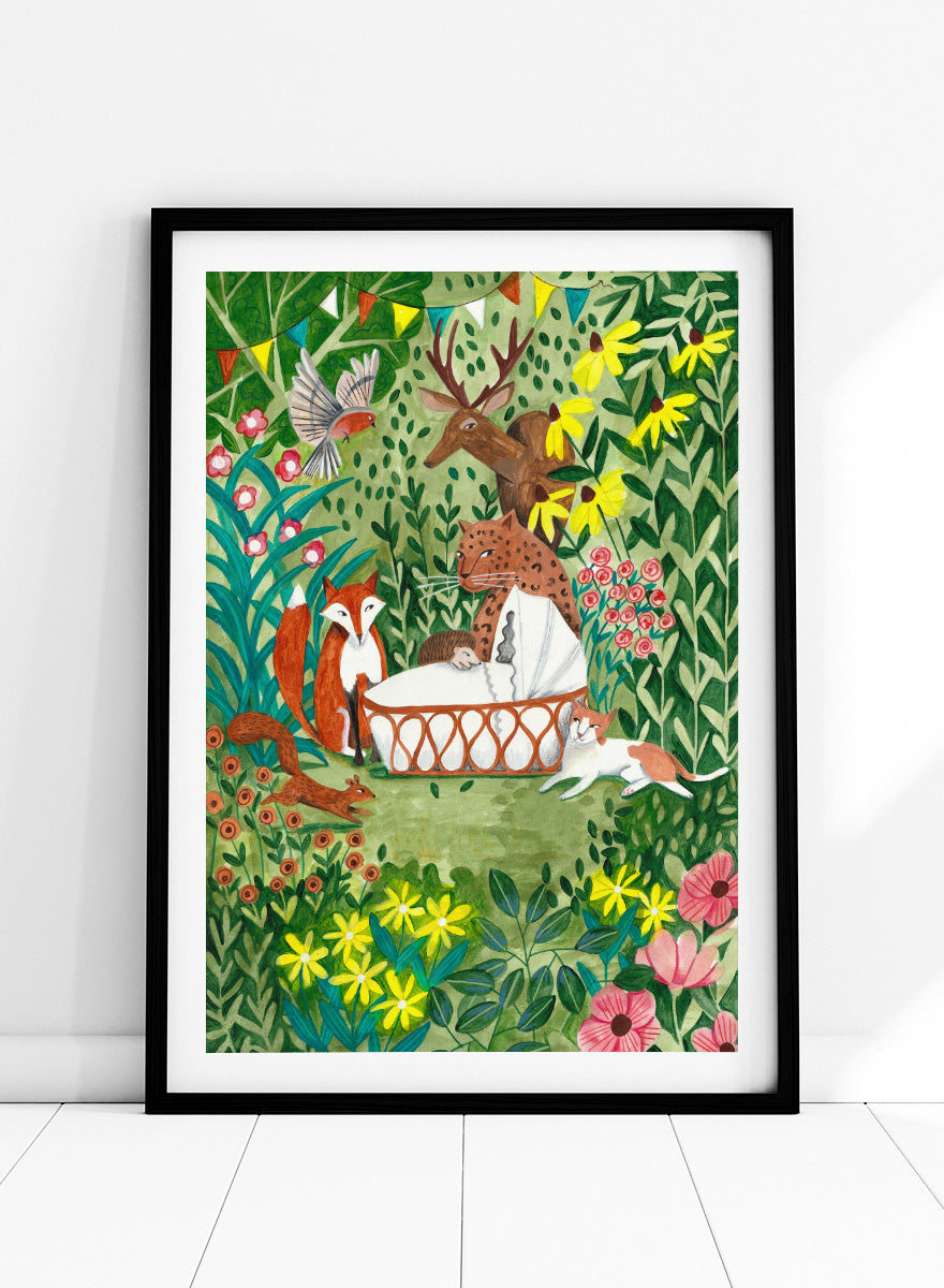 A framed art print featuring a whimsical forest illustration with animals gathered around a basket, surrounded by flowers and foliage. The print is shown with a white mat and a black frame against a white background. Welcome to the Forest by Caroline Bonne Müller woodland animal art print featuring a baby surrounded by a leopard, fox, deer, cat, flowers, and forest life.