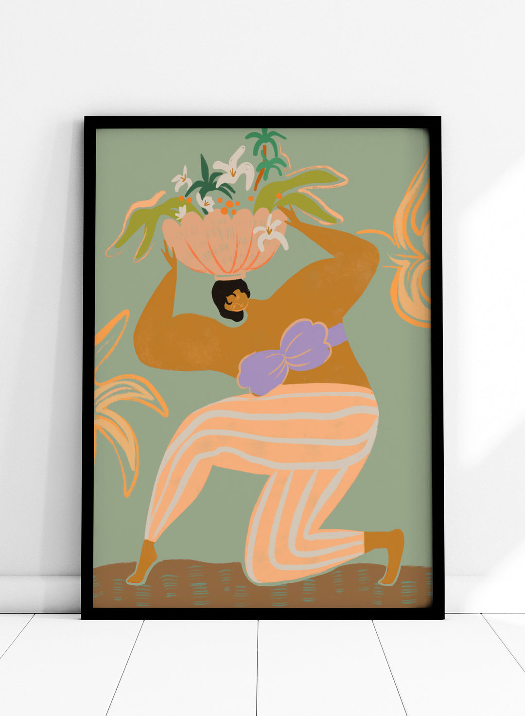 A stylized art print featuring a woman in flowing peach and white striped pants with a purple sash, carrying a large flower basket on her head against a muted sage green background. The Weight of the World by Arty Guava premium framed fine art print featuring a woman carrying tropical flowers in soft green, peach, and lilac tones.
