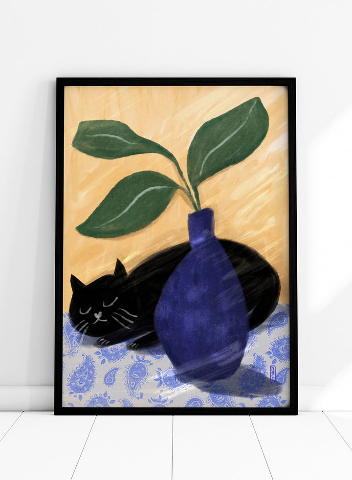 A stylized still life painting featuring a black cat lying on a blue-and-white patterned surface beside a dark blue vase with green leaves, against a warm beige background. Shop the Sleeping Black Cat art print by Dirkie Nell, featuring a curled black cat, bold cobalt blue vase, green leaves and playful patterned details.