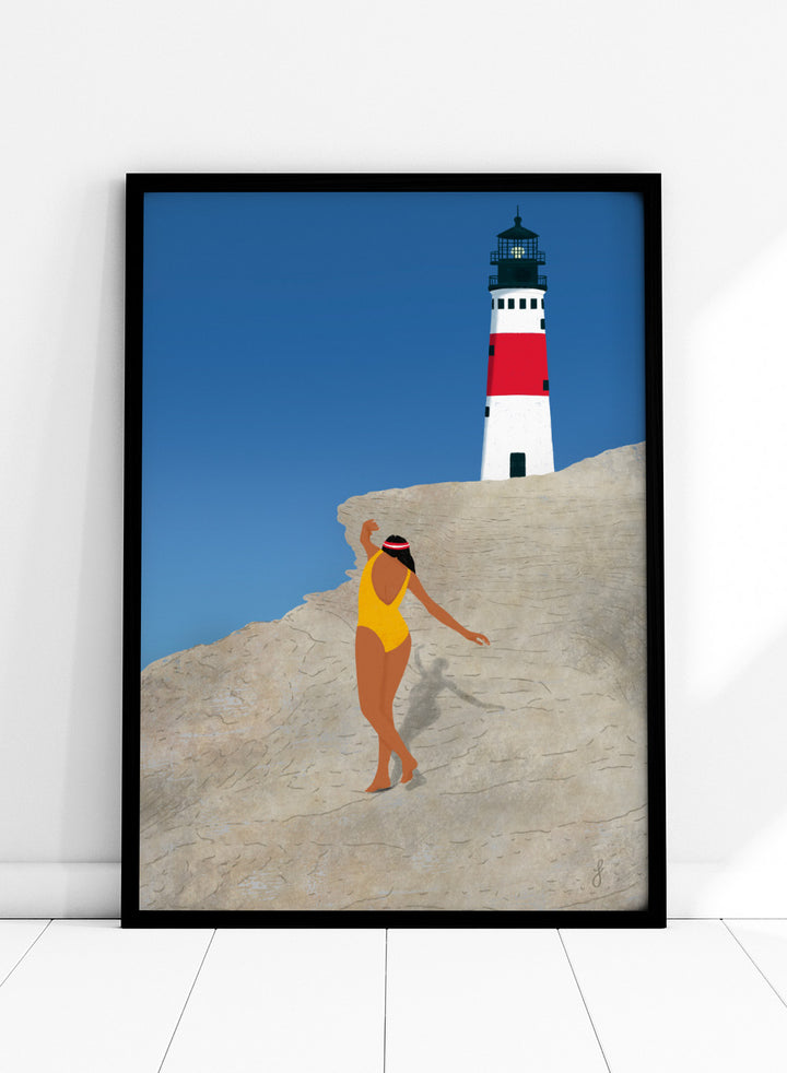 Woman in a yellow swimsuit standing on a rocky outcrop with a lighthouse in the background. My Beach by Jota de Jai is a modern coastal wall art print featuring a woman in a yellow swimsuit and a lighthouse. Officially licensed fine art poster with optional wood frame.