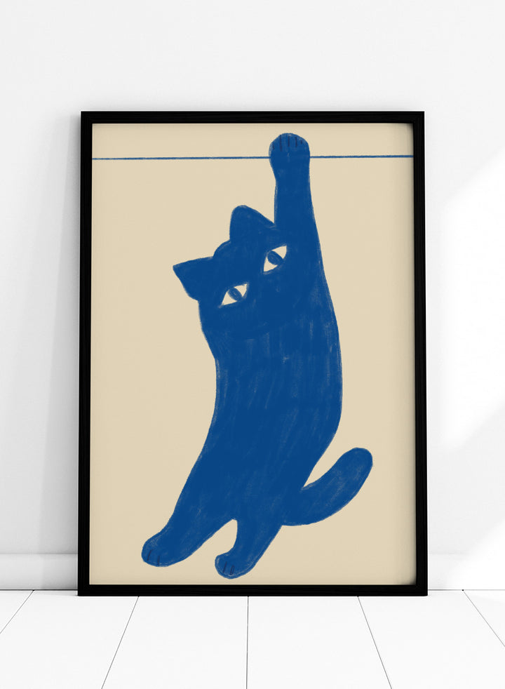 A stylized blue cat silhouette hanging from a thin horizontal line on a warm beige background. Hanging Blue Cat by The Art Concept is a playful cat art print featuring a blue cat dangling from one paw against a warm cream background.