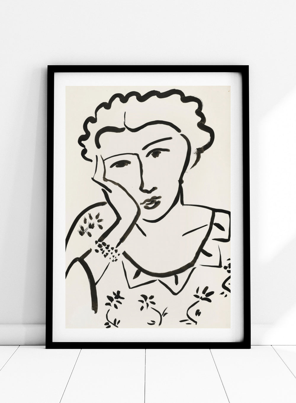 Black line art of a woman with floral patterns on a white background. Jeune Fille Accoudée by Henri Matisse is a minimalist portrait art print featuring expressive black linework, floral detailing, and refined French modernist design.