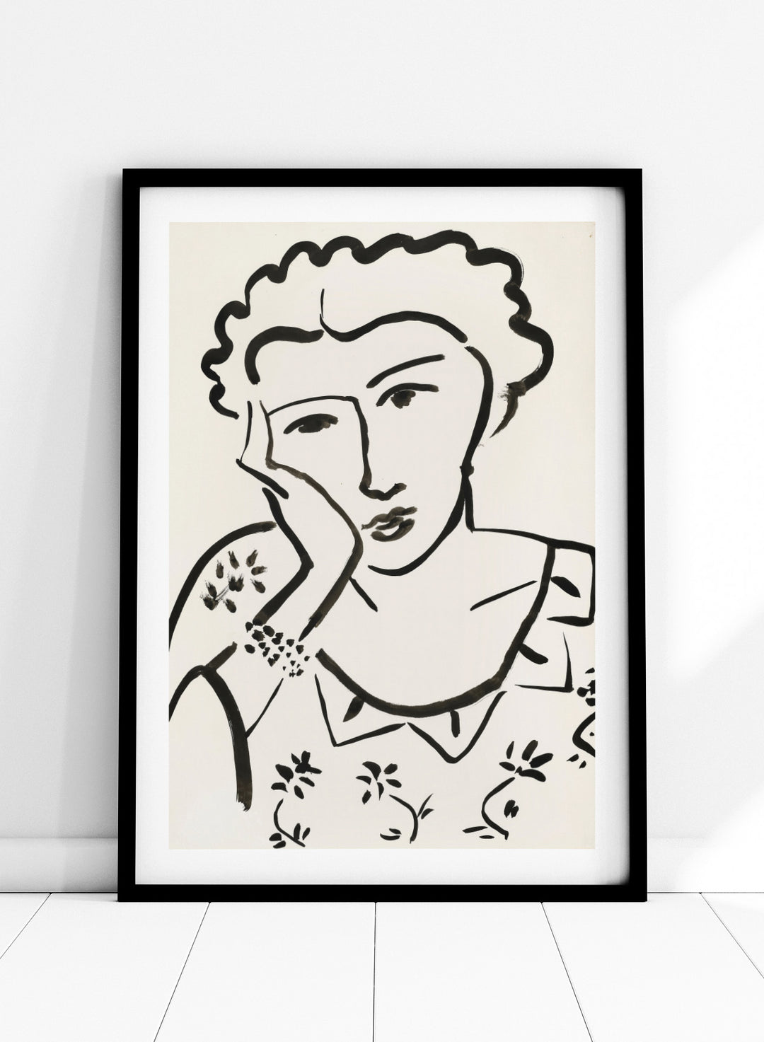 Black line art of a woman with floral patterns on a white background. Jeune Fille Accoudée by Henri Matisse is a minimalist portrait art print featuring expressive black linework, floral detailing, and refined French modernist design.