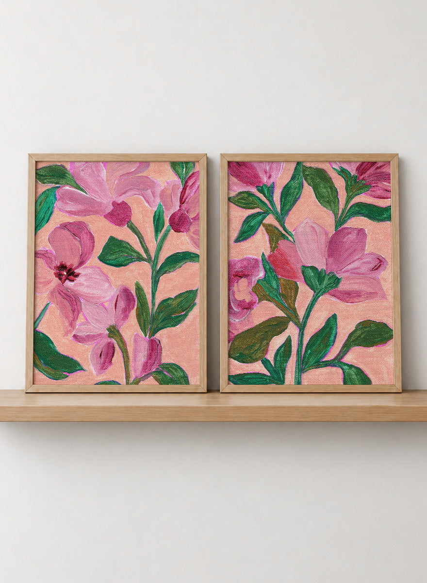 Two framed floral art prints with pink flowers and green leaves on a peach background. Shop Vibrant Pink Botanicals by Nikita Jariwala, a set of 2 floral wall art prints posters featuring oversized pink flowers and lush botanical artwork.