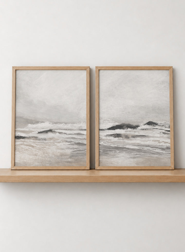 Shop September Coast by Dan Hobday, a set of 2 coastal wall art prints posters featuring rolling waves, dark rocks, misty skies, and soft neutral tones.