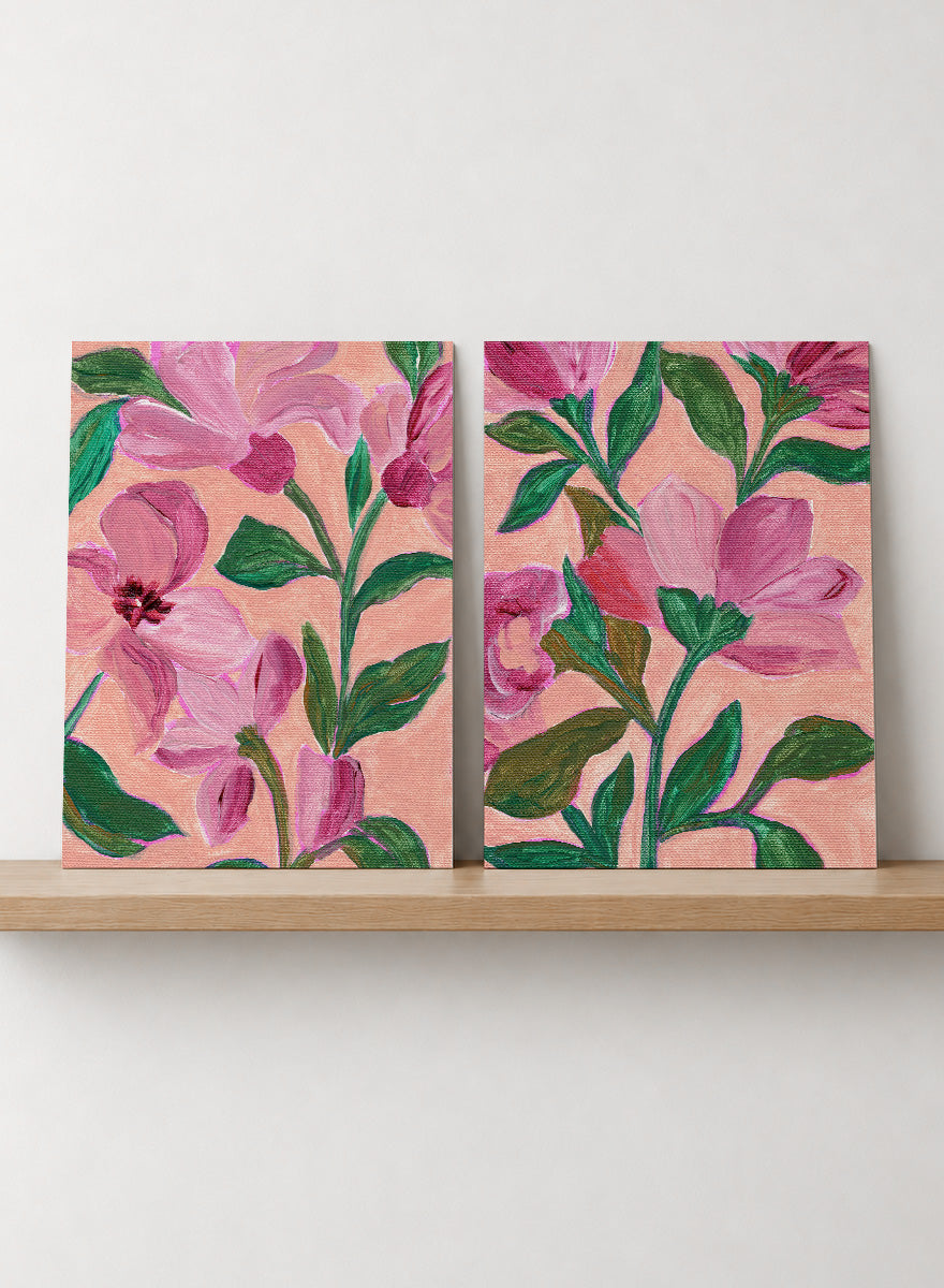 Two framed floral art prints with pink flowers and green leaves on a peach background. Shop Vibrant Pink Botanicals by Nikita Jariwala, a set of 2 floral wall art prints posters featuring oversized pink flowers and lush botanical artwork.