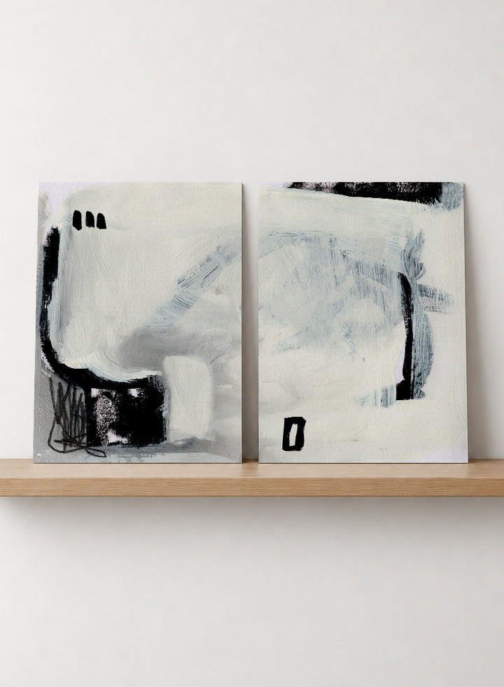 Shop Beyond by Dan Hobday, a set of 2 abstract wall art prints posters featuring expressive black forms, layered brushwork, and soft white and blue tones.