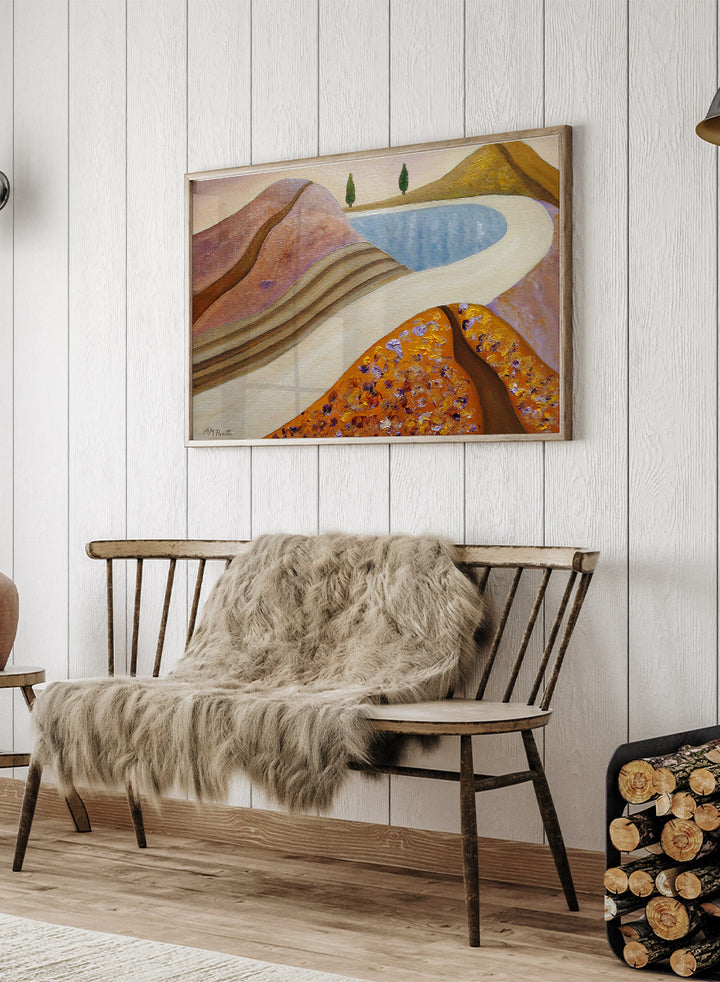 A framed landscape painting featuring stylized hills, a winding cream path, a blue pool, and two small green trees. Shop Peaceful Hills and Lake by Angeles M. Pomata, a serene landscape art print featuring a blue lake, rounded hills, winding paths, and soft earthy tones.