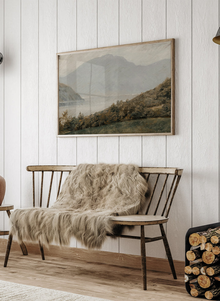 A framed landscape painting depicting a misty mountain range over a body of water with trees in the foreground. Landscape with Mountains in the Background by Susette Holten is a vintage mountain landscape print featuring a lake, misty peaks, trees, and muted natural tones.