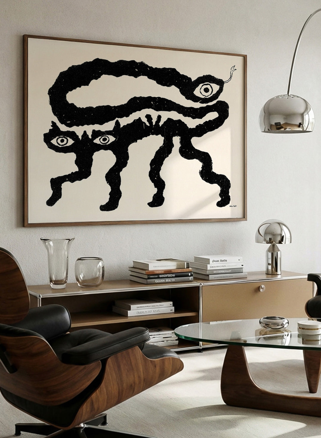 Framed artwork of a black and white creature with cat-like features and snake-like body. I Am Animals by Eden Kalif is a modern minimalist line art print featuring abstract animal forms in a bold black and white contemporary wall poster design.