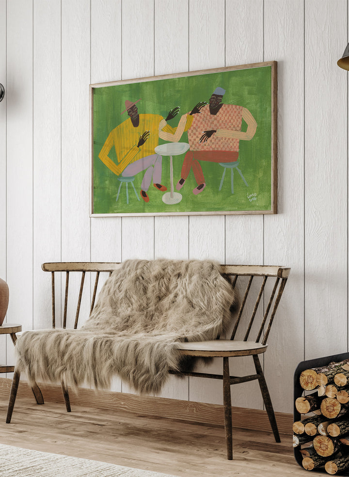 Framed artwork of two people sitting at a table on a green background. In Good Company by Studio IMO (Ibi Meier-Oruitemeka) is a modern figurative art print featuring two figures at a table in a bold contemporary wall poster design.