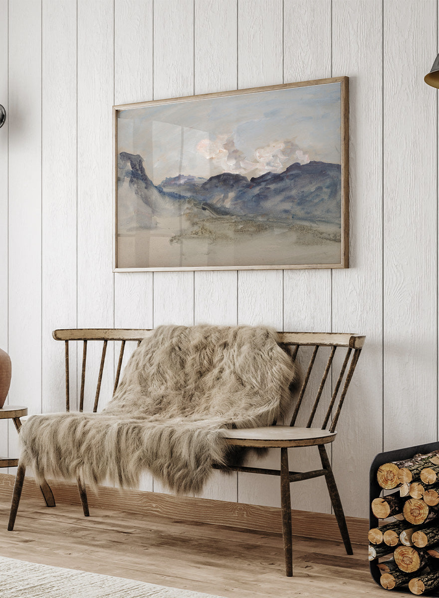 A framed landscape painting featuring blue and gray mountains under a pale sky with soft white clouds. In the Alps by Hercules Brabazon Brabazon is a vintage watercolor art print featuring snowy peaks, blue-grey mountains, soft clouds, and a misty alpine view.