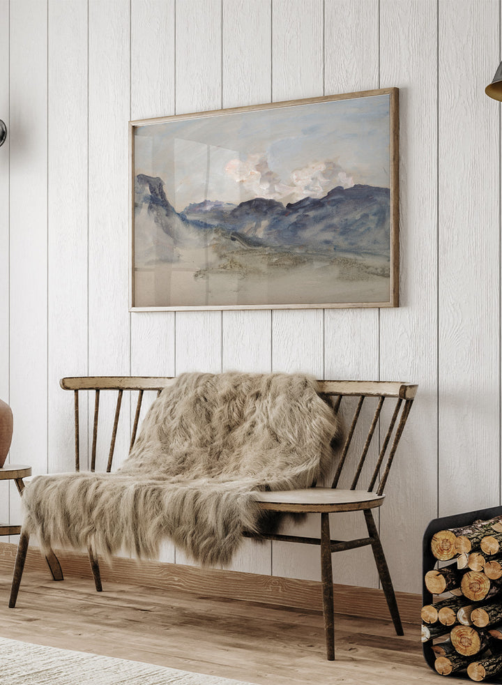 A framed landscape painting featuring blue and gray mountains under a pale sky with soft white clouds. In the Alps by Hercules Brabazon Brabazon is a vintage watercolor art print featuring snowy peaks, blue-grey mountains, soft clouds, and a misty alpine view.