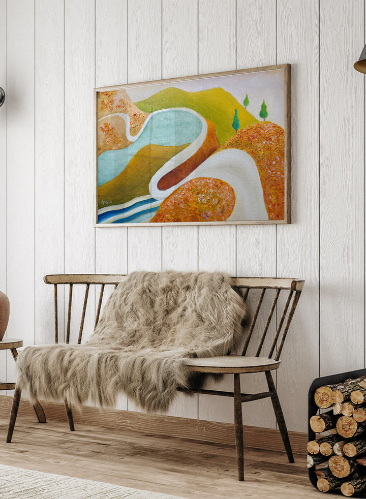 A framed abstract landscape painting featuring winding light blue and white river-like curves, green hills, and textured orange-brown foreground shapes. Shop Serene Valley Path by Angeles M. Pomata, a colorful landscape art print featuring a winding path, river, rolling hills, and warm earthy tones.