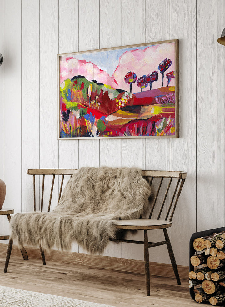 A framed abstract landscape painting featuring pink clouds, green hills, and colorful stylized trees. Shop Vibrant Fantasy Landscape by Dirkie Nell, a colorful landscape art print featuring pink clouds, rolling hills, wildflowers, and bold abstract color.