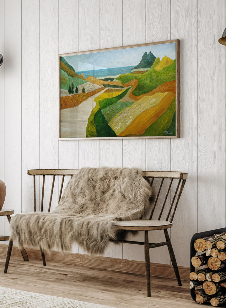 A framed landscape painting featuring a winding cream-colored path through green and ochre hills, leading to a blue sea and distant mountain under a pale sky. Shop Vibrant Coastal Vista by Angeles M. Pomata, a colorful coastal landscape art print featuring winding roads, rolling fields, rugged hills, and blue sea views.