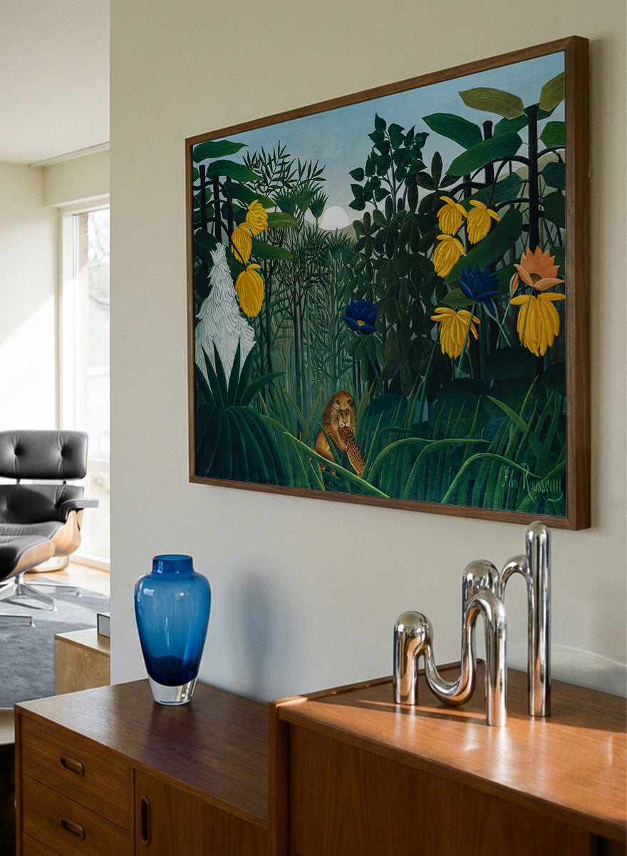 A framed art print depicting a lush jungle scene with green foliage, yellow flowers, blue and orange blossoms, and a small lion near the bottom center. The Repast of the Lion by Henri Rousseau is a vintage jungle art print featuring a lion hidden among dense tropical foliage and lush green plants.