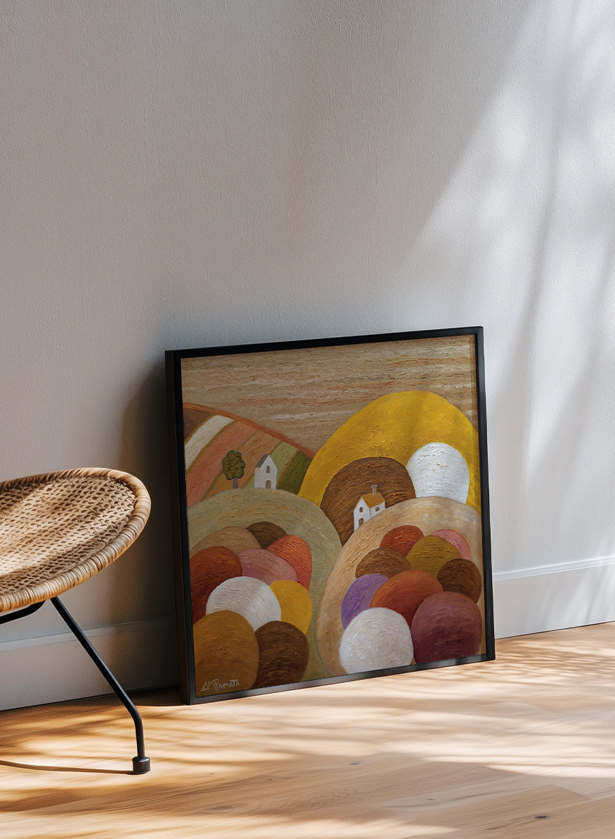 A framed abstract landscape painting featuring stylized hills, rolling forms, small houses, and a large yellow circular shape. Shop Colorful Hillside Village by Angeles M. Pomata, an autumn landscape art print featuring rounded hills, tiny white houses, earthy tones, and rich oil texture.