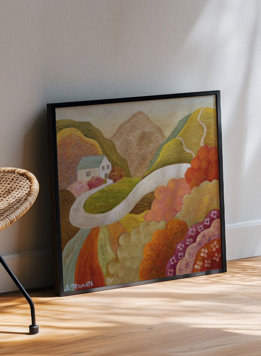 A framed landscape painting featuring a winding white road through colorful hills, a small white house, and a mountain in the background. Shop Colorful Hillside Home by Angeles M. Pomata, an autumn landscape art print featuring a winding road, white country house, rolling hills, and wildflowers.