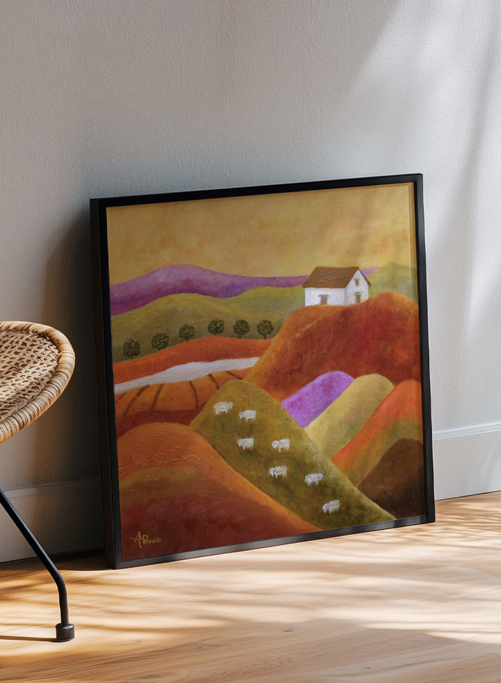 A framed landscape painting featuring rolling hills in warm earth tones, purple and green valleys, a small white house, and white sheep. Shop Pastoral Hills With Sheep by Angeles M. Pomata, an autumn countryside art print featuring rolling hills, grazing sheep, a white farmhouse, and warm earthy tones.