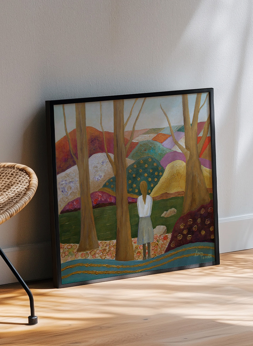 A framed landscape painting featuring a woman standing among tall trees, looking over a patchwork field of hills in earthy tones of green, purple, orange, and beige. Shop Woman Among Vibrant Hills by Angeles M. Pomata, a colorful landscape and portrait art print featuring a woman, rolling hills, trees, and earthy tones.