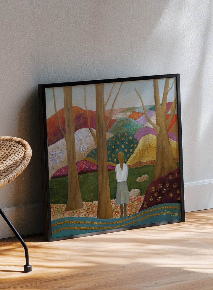 A framed landscape painting featuring a woman standing among tall trees, looking over a patchwork field of hills in earthy tones of green, purple, orange, and beige. Shop Woman Among Vibrant Hills by Angeles M. Pomata, a colorful landscape and portrait art print featuring a woman, rolling hills, trees, and earthy tones.