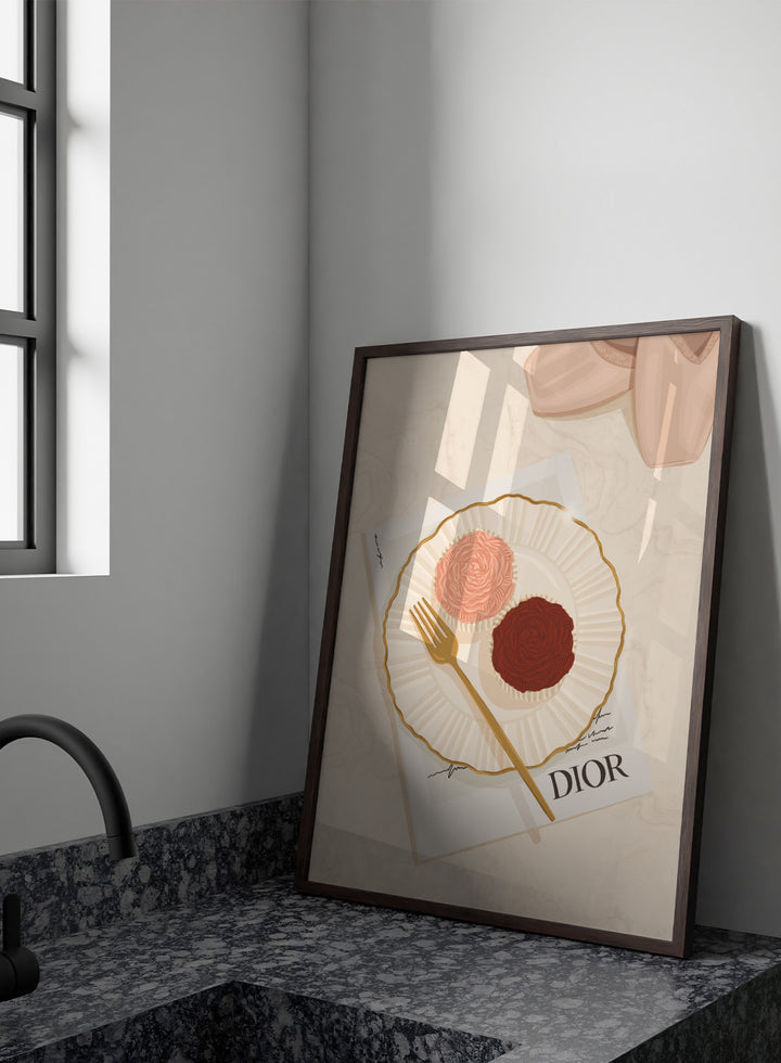A stylized flat-lay illustration featuring a white plate with a gold rim holding two rose-shaped pastries, one light pink and one dark chocolate brown, with a gold fork on top. Elegant Cupcakes Ballet Shoes by Lisa Solomoniuk premium framed fine art print featuring pink ballet shoes, frosted cupcakes, and gold details.