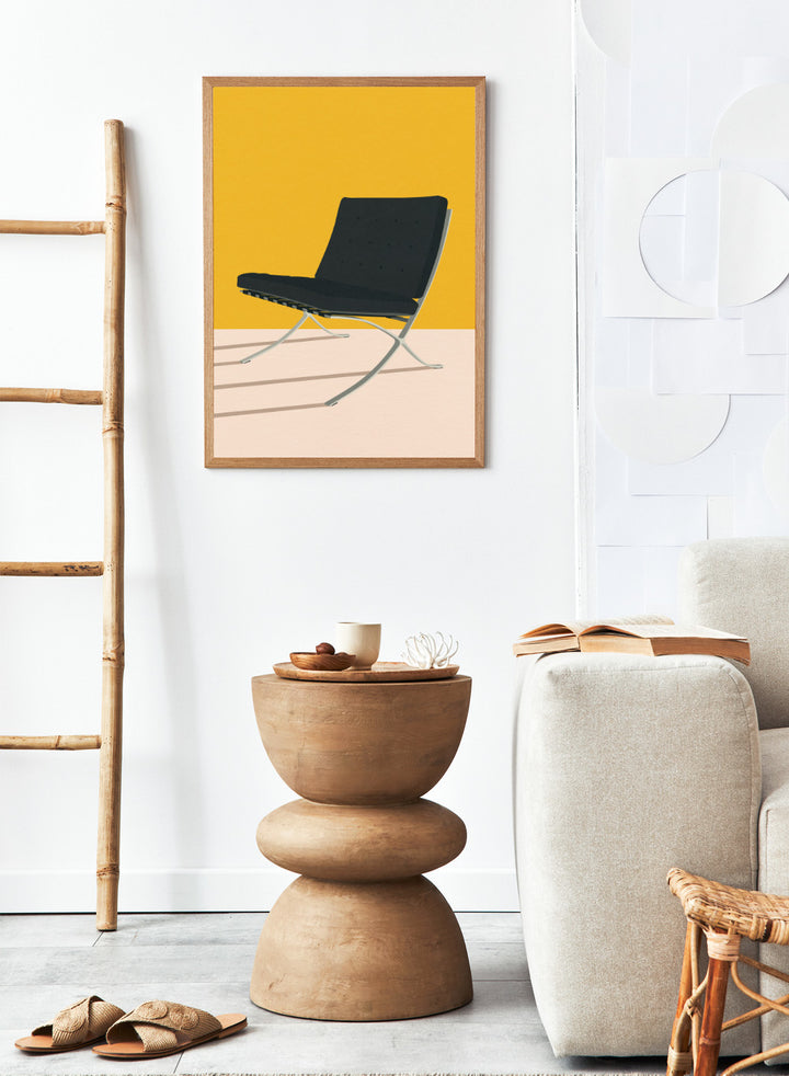 Black chair with metal legs on a yellow and beige background. Barcelona Chair by Mies Van Der Rohe by Rosi Feist is a minimalist modern design art print featuring clean lines and bold color. Officially licensed fine art poster with optional real wood framing, ready to hang.