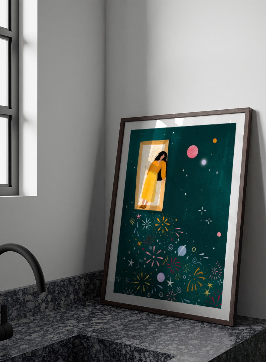 A framed art print featuring a whimsical illustration of a woman in a yellow dress standing in a mirror, with her reflection spreading colorful fireworks and space-themed motifs like planets and stars across a dark teal background. Shop Girl and Cosmic Fireworks by Bea Müller, a figurative wall art print poster featuring a woman, planets, stars, and colorful cosmic fireworks in deep green tones.