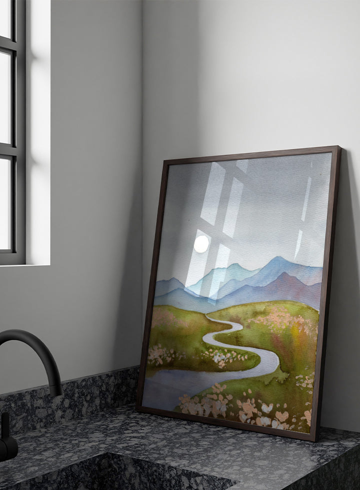 Watercolor landscape painting of a winding river flowing through green hills with pink flowers, blue mountains in the background, and a white sun in a gray sky. Shop Serene Mountain Path by Ekaterina Prisich, a landscape art print featuring a winding valley path, blue mountains, soft flowers, and a white moon.