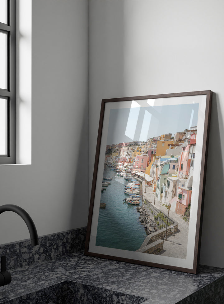 Colorful coastal town with boats docked along a waterfront. Colorful Italian Harbor by Henrike Schenk is a coastal photography print featuring pastel waterfront architecture, fishing boats, turquoise waters, and Mediterranean charm.