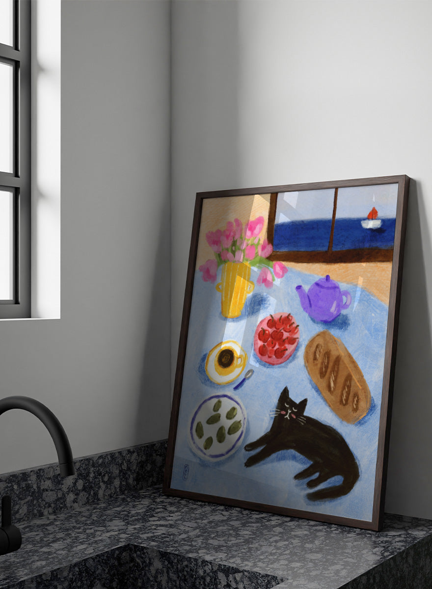 A colorful still life painting of a table scene with pink tulips in a yellow vase, a purple teapot, a bowl of strawberries, a cup of coffee, a loaf of bread, a black cat, and a window view of the sea with a small sailboat. Shop Relaxing Seaside Cat Breakfast by Dirkie Nell, a playful cat and food art print featuring breakfast, flowers, a sailboat, and a seaside view.