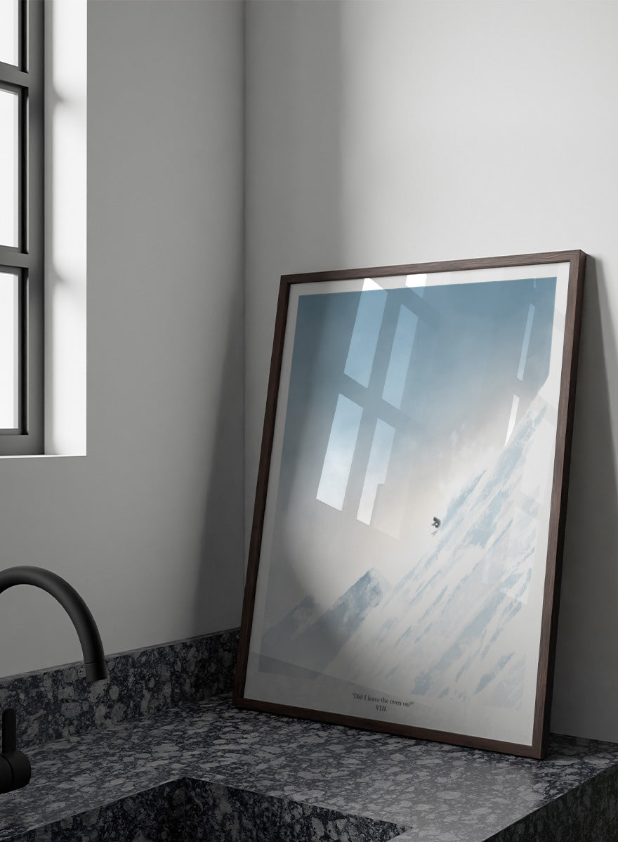 A framed art print featuring a minimalist illustration of a skier on a snowy mountain slope under a pale blue sky, with the text &