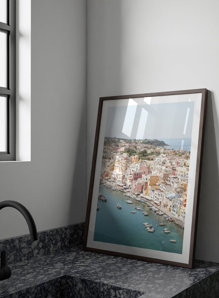 Coastal town with colorful buildings and boats in a harbor. Vibrant Italian Coastal Town by Henrike Schenk is a coastal photography print featuring pastel architecture, turquoise waters, fishing boats, and Mediterranean charm.