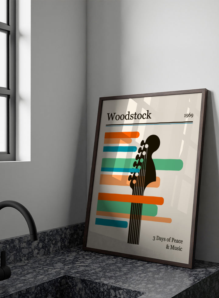 A graphic poster-style design for Woodstock 1969, featuring a black guitar headstock silhouette layered over horizontal orange, teal, and blue bars on a warm cream background. The text reads &