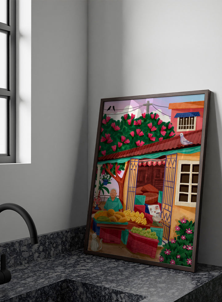 A colorful illustrated street market scene with a vendor standing behind tables of fruit and vegetables, a flowering tree, a house with pink flowers, crates, a pigeon on the roof, birds in the sky, and a white cat in the lower left. Colorful fruit stand art print by Nidhi Kachhadiya with fresh produce, floral details, and market charm. A cheerful print for kitchen or dining spaces.