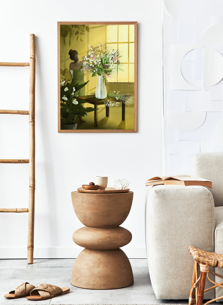 Woman in a green dress holding a bouquet of flowers in a softly lit room. In the Cracks of Light I Dream by Goed Blauw is a floral art print and wall poster featuring a woman arranging flowers in warm window light.