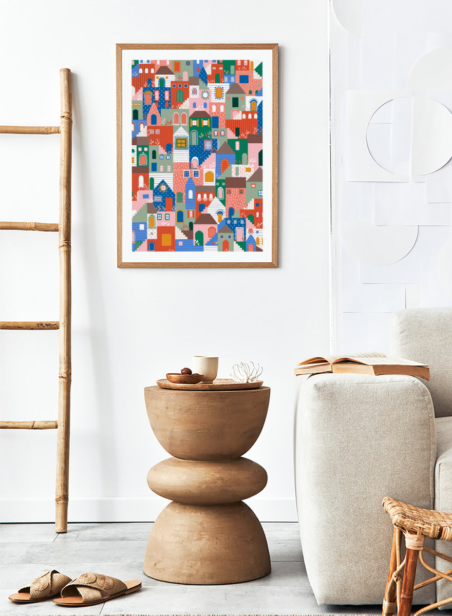 A colorful art print featuring a dense, stylized illustration of houses and buildings in a playful, patterned village scene. Whimsical Cityscape Charm by Ceyda Alasar city art print featuring stacked colorful houses, patterned walls, winding stairs, and playful architectural details.