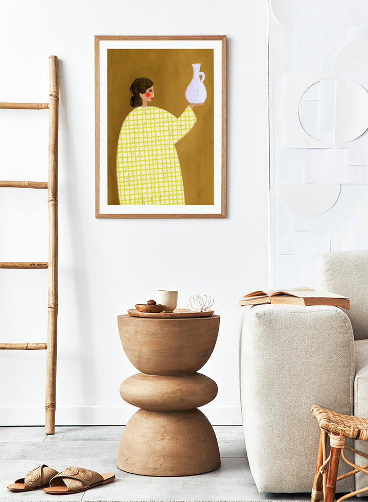 A framed art print featuring a stylized illustration of a woman in a yellow and white checkered dress holding a white jug against a warm brown background. Woman Holding Pottery by Bea Müller art print featuring a woman with a white ceramic jug, bold green checks, and warm mustard tones for modern decor.