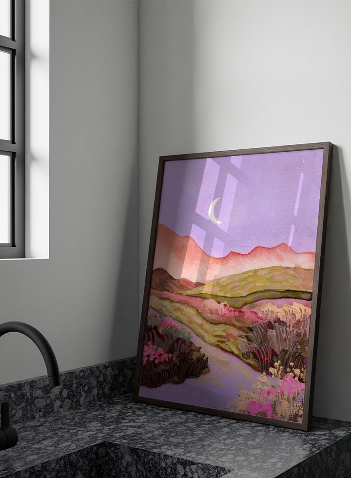 A landscape painting featuring rolling green hills, pink mountains, a purple sky with a crescent moon, and pink flowers along a winding path. Shop Moonlit Valley Path by Ekaterina Prisich, a colorful landscape art print featuring a crescent moon, winding path, rolling hills, and wildflowers.