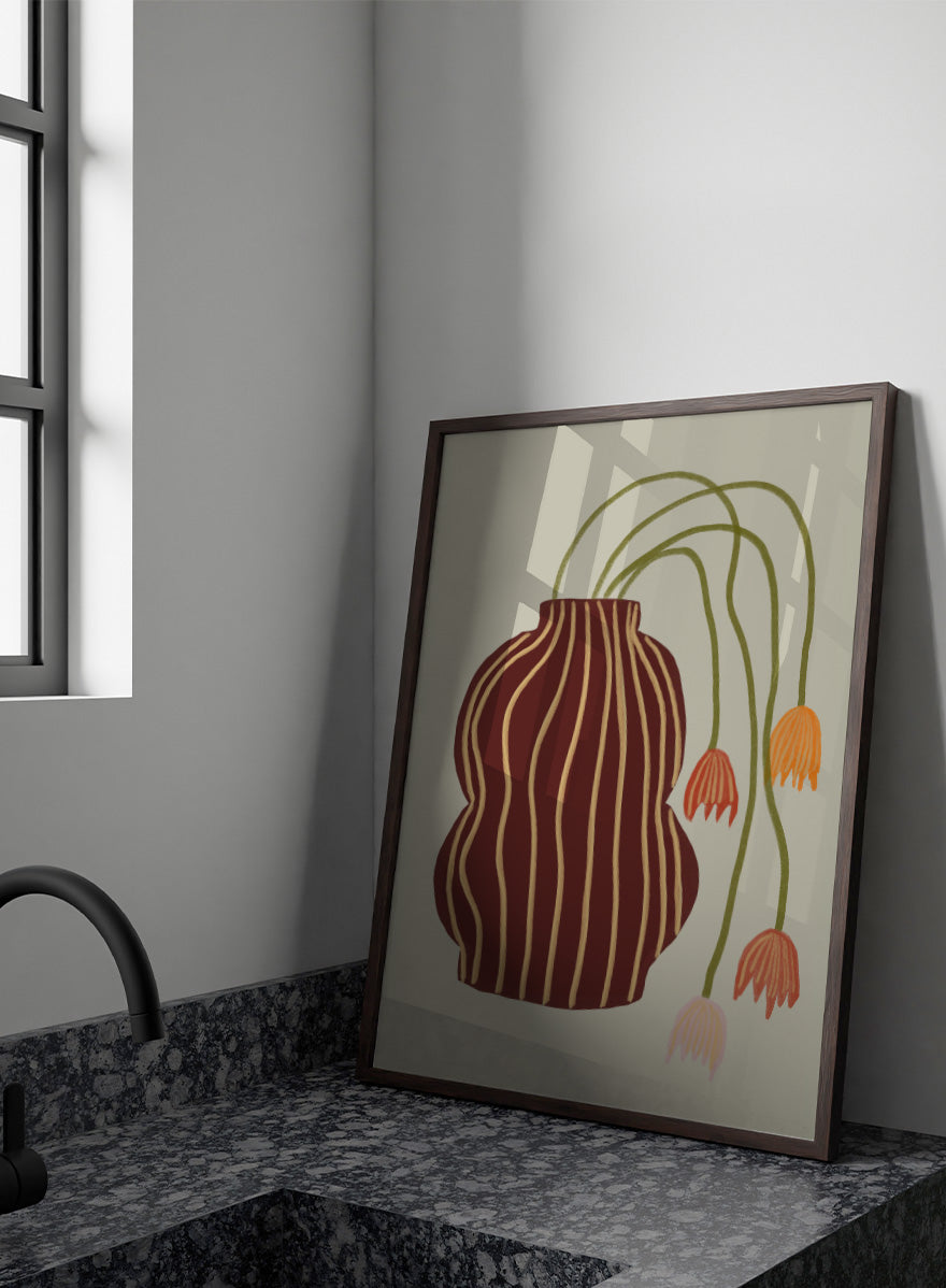 A stylized botanical art print featuring a dark brown vase with vertical gold stripes and several trailing flowers in orange, pink, and olive green on a warm beige background. Striped Vase Drooping Flowers by The Art Concept art print featuring a burgundy striped vase and soft drooping blooms in warm earthy tones.