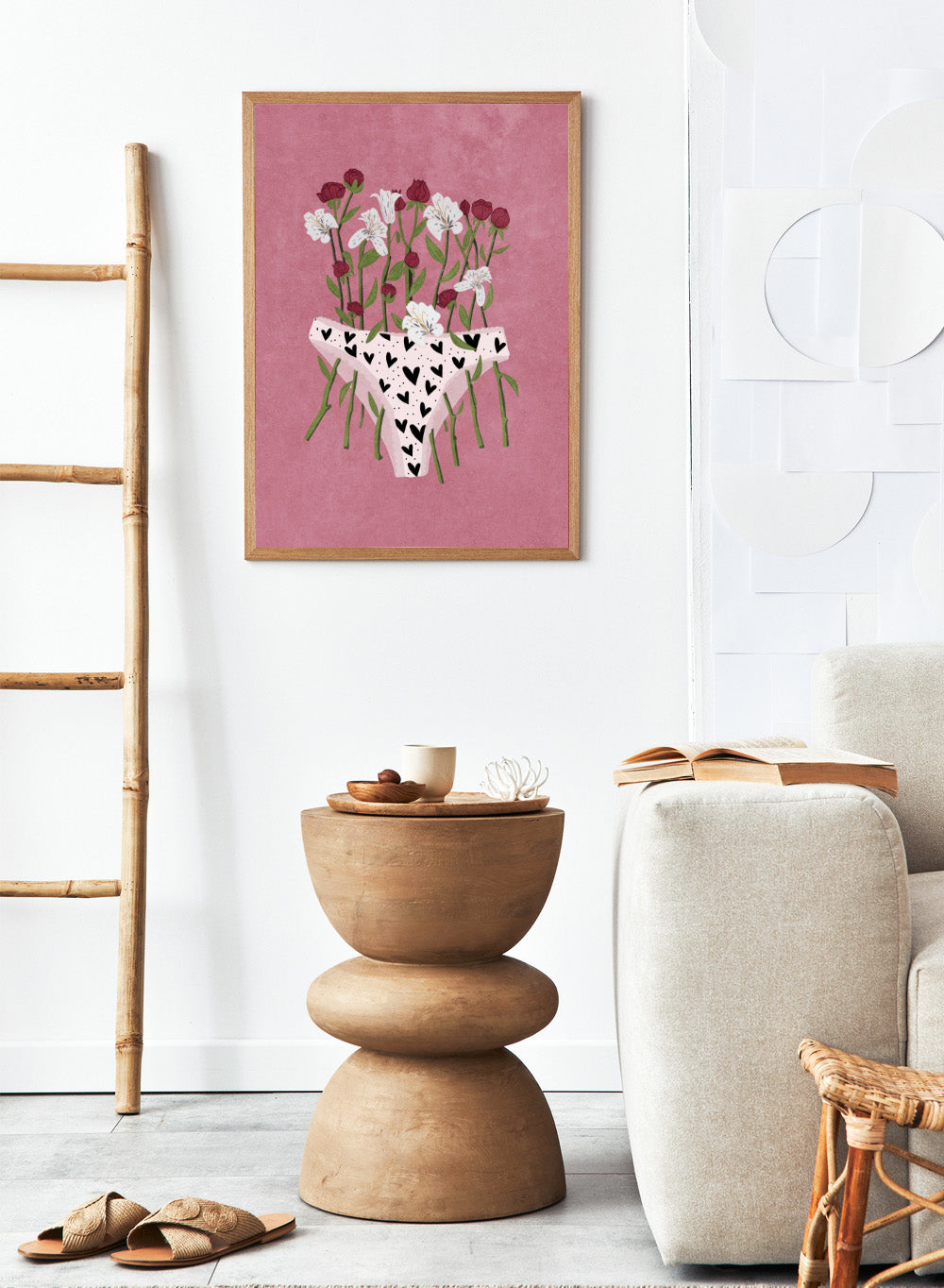 White underwear with black heart patterns surrounded by flowers on a pink background. Blooming Slip by Raissa Oltmanns features a feminist illustration of flowers growing from heart-patterned underwear on a pink background. Bold floral art print with strong feminine symbolism.