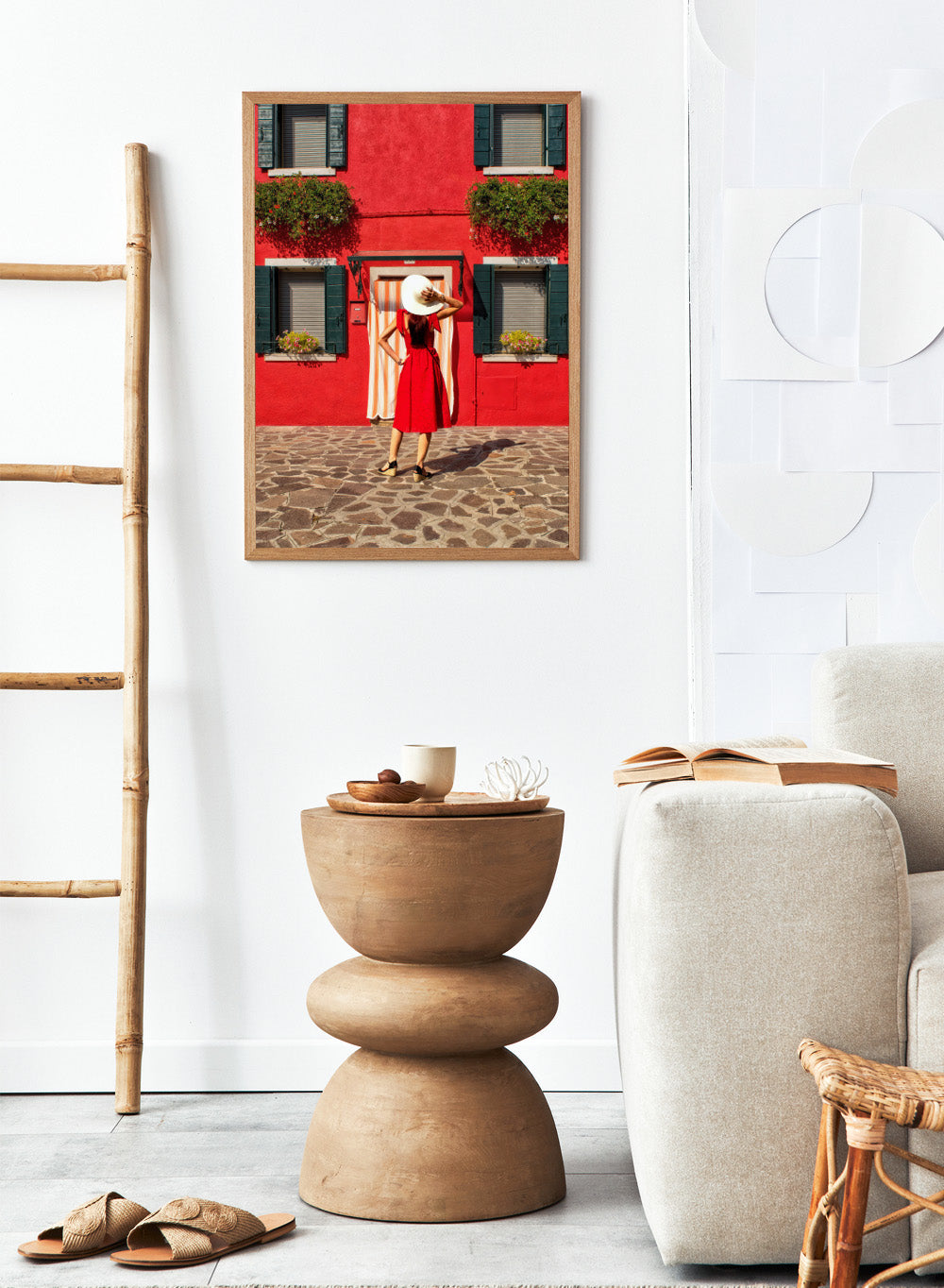 Woman in a red dress and white hat standing in front of a red wall with green shutters. Red Art Print by Anette Ohlendorf featuring a woman in a red dress standing against a red building. Officially licensed travel photography with strong color and symmetry.