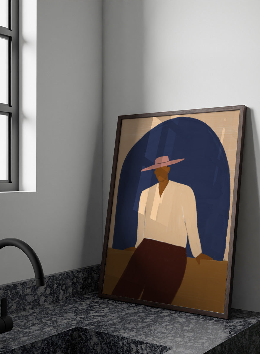 A stylized art print depicting a seated figure in a wide-brimmed pink hat, cream shirt, and dark brown trousers against a large dark blue arch on a beige background. Man In Blue Arch by The Art Concept portrait art print featuring a lone figure beneath a deep blue arch in warm earthy tones.