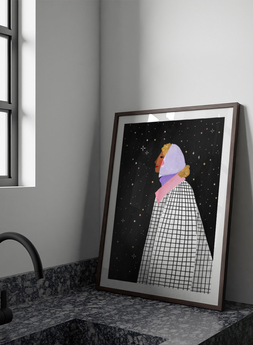 A framed art print featuring a stylized illustration of a woman in profile wearing a white and black checkered cape and a lavender headscarf against a black starry background. Shop Woman Under Starry Night by Bea Müller, a figurative wall art print poster featuring a contemplative woman beneath a star-filled black night sky.