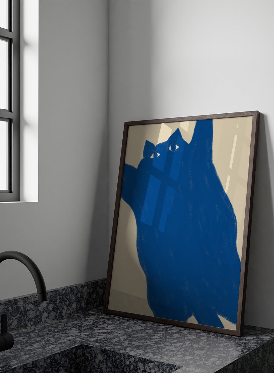 A minimalist art print featuring a bold blue cat silhouette with white eyes on a warm beige background. Playful Blue Cat by The Art Concept is a modern cat art print featuring a bold blue feline, oversized crop, and warm cream background.