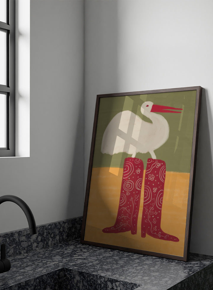 A stylized art print featuring a white stork with a red beak standing on a pair of tall red boots with white swirl patterns, set against a muted green and ochre background. Bird in Red Boots by The Art Concept playful animal art print featuring a white bird in oversized red patterned boots with soft green and ochre tones.